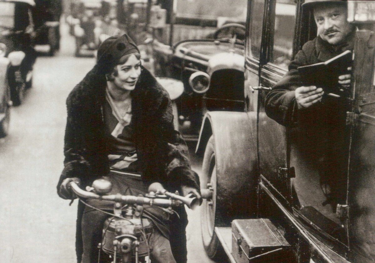 Vintage - Stil Postkarte: Elegante Frau auf Fahrrad - Schwarz - Weiß Retro Fotografie, 20er Jahre Mode & Nostalgie, Städtische Alltagsszene mit Hut und Gespräch - Ideal für Sammler & Kommunikation